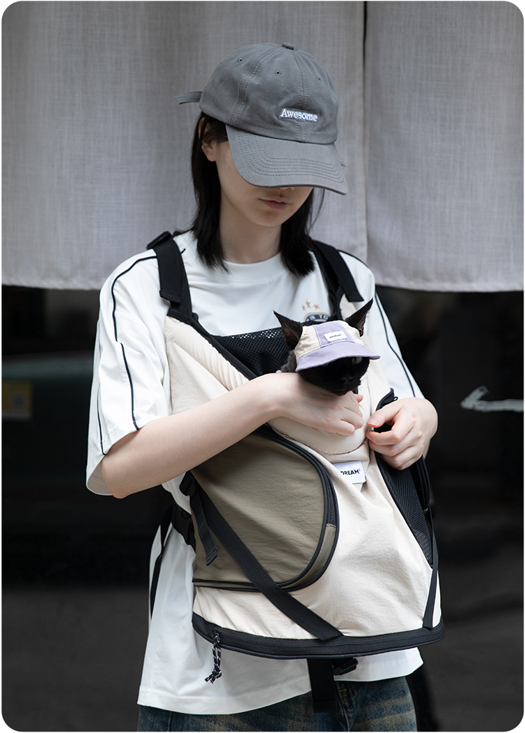 Black cat wearing a Hibiscus Purple cat sun hat while being carried in a pet carrier